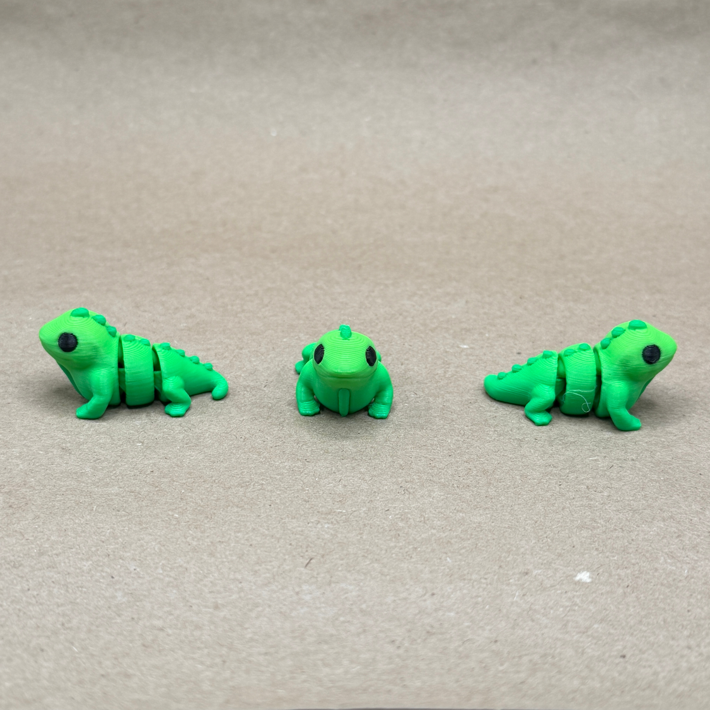 Three angles of 3D printed articulated iguana fidget toy — front, side, and rear views